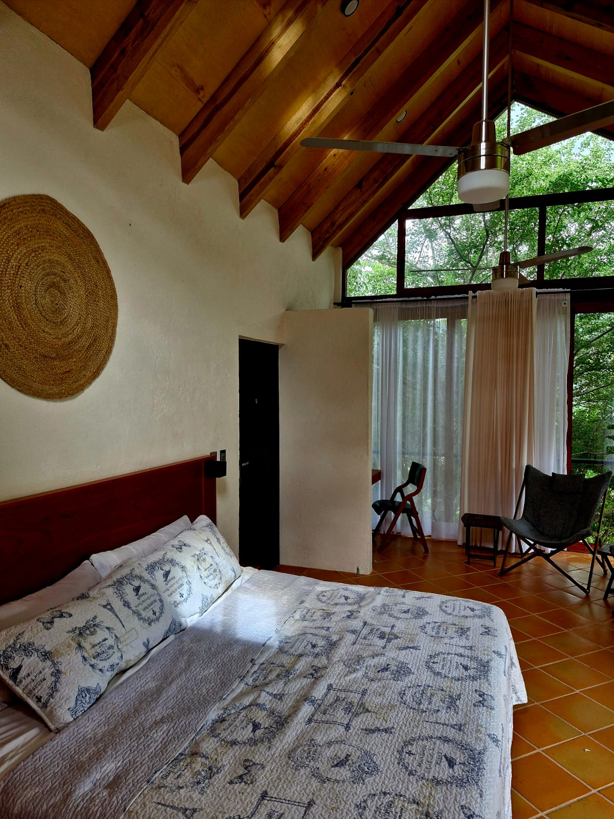 Interior de la Cabaña Las Águilas mostrando la cama matrimonial y la zona de descanso con sillas.
