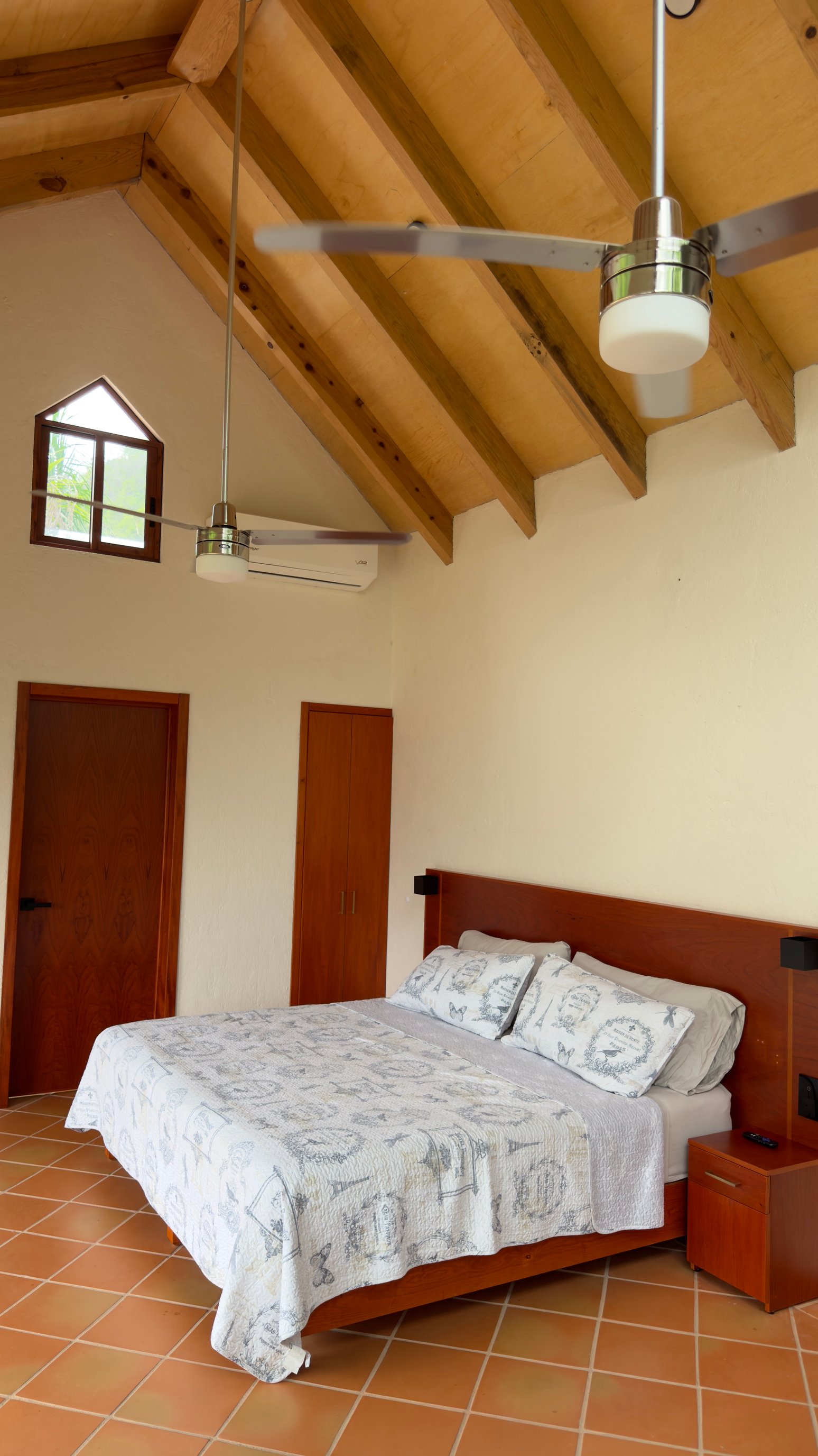 Cama matrimonial en la Cabaña Las Águilas bajo techo de madera y ventilador.