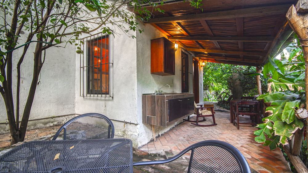 Terraza de la Cabaña Mariposas con cocineta, mesas exteriores y vegetación alrededor