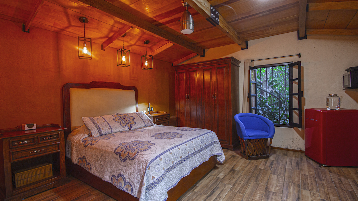 Habitación de la Cabaña Mariposas con cama Queen, decoración cálida, clóset de madera y ventana con vista al jardín