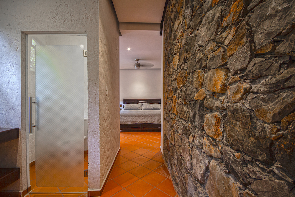 Interior de la Habitación El Cardenal con cama king size, escritorio, ventilador de techo y ventanal hacia la terraza.