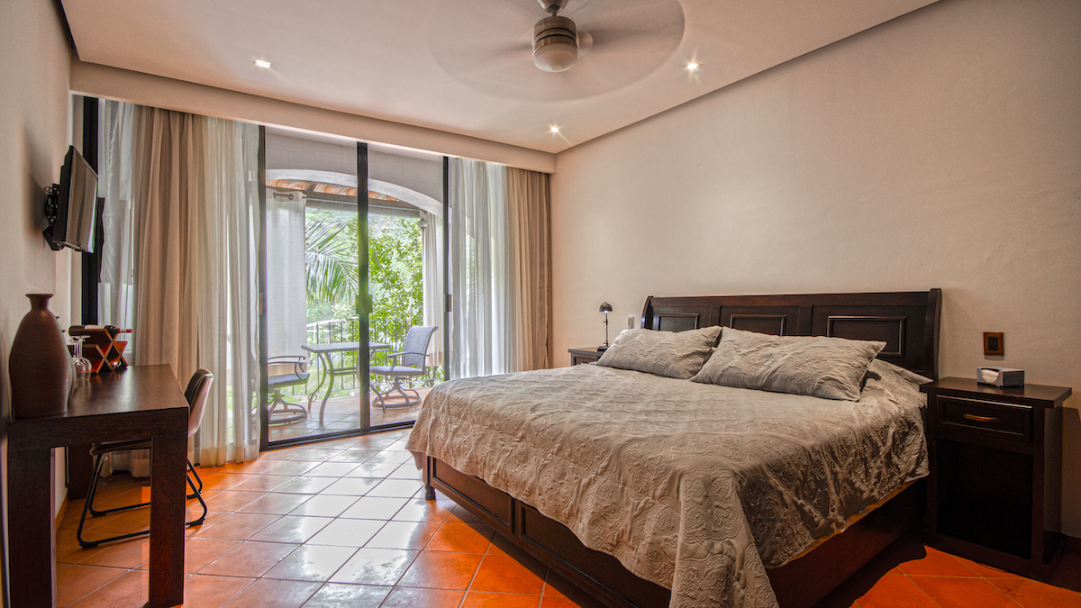 Baño de la Habitación El Cardenal con lavamanos de madera, ventana decorada y ducha al costado.