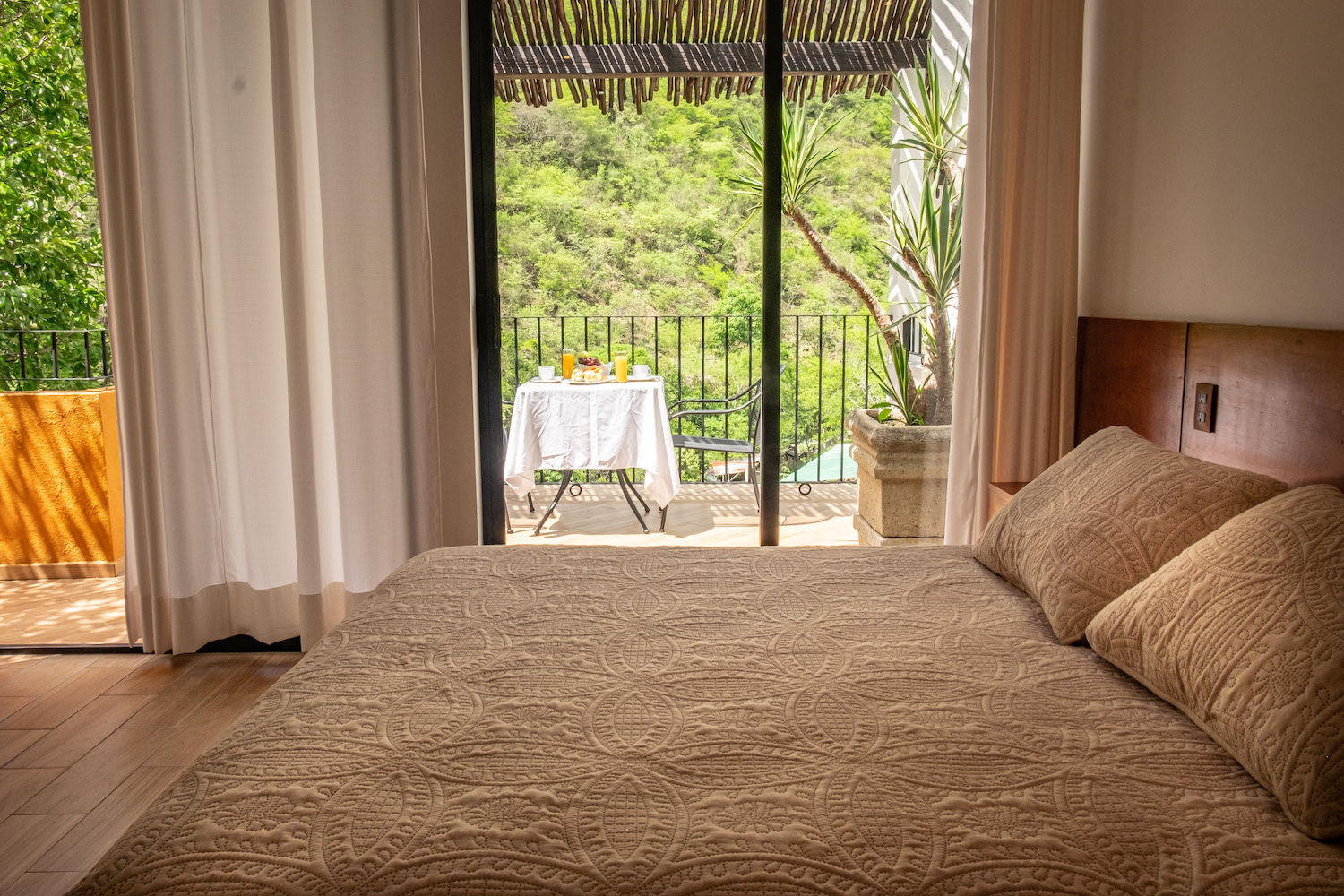 Cama matrimonial en la Habitación El Palomar con ventanales a la terraza y vista al paisaje.