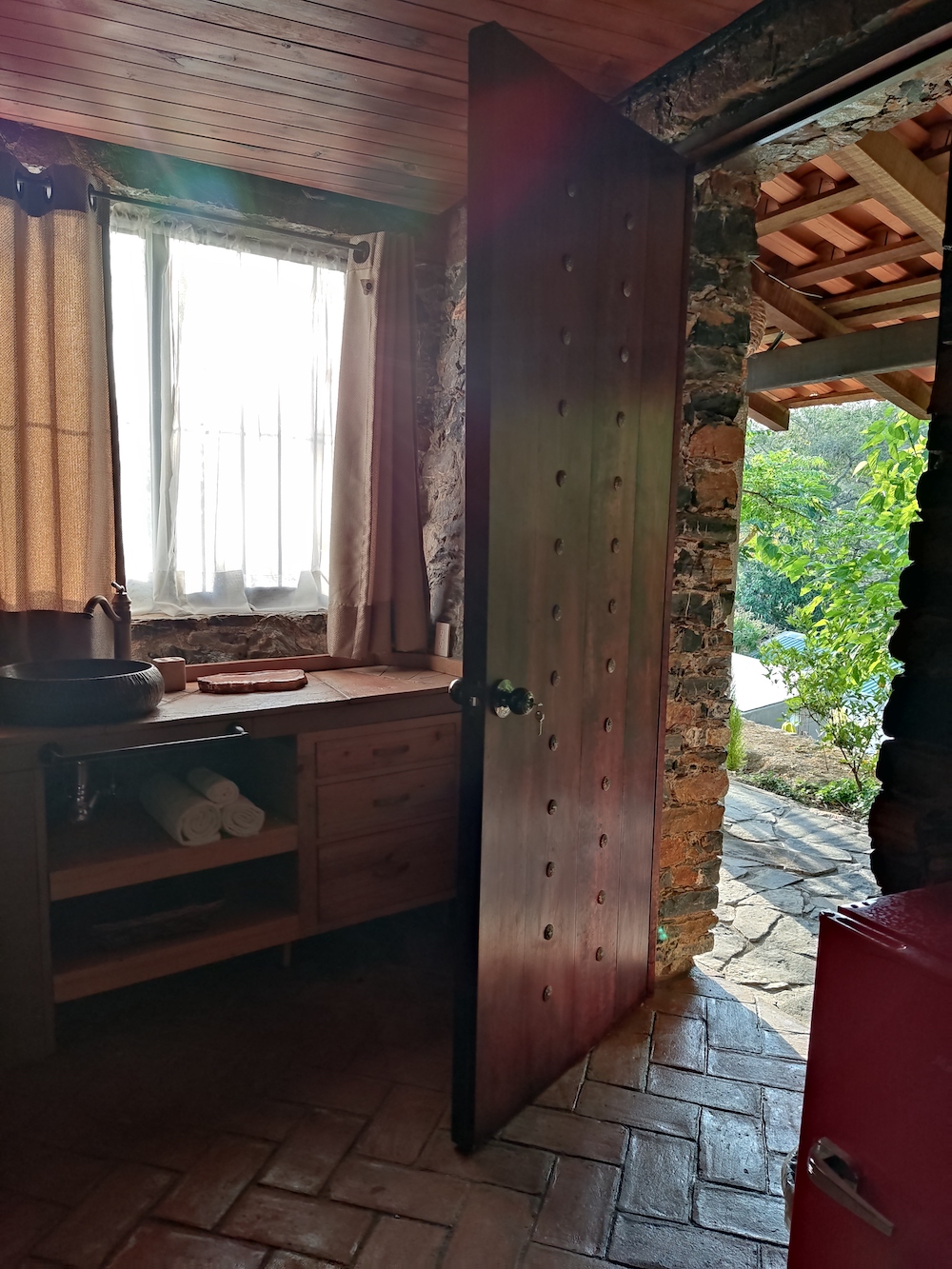 Interior de la Habitación San Francisco con mueble, lavamanos y vista a la entrada.